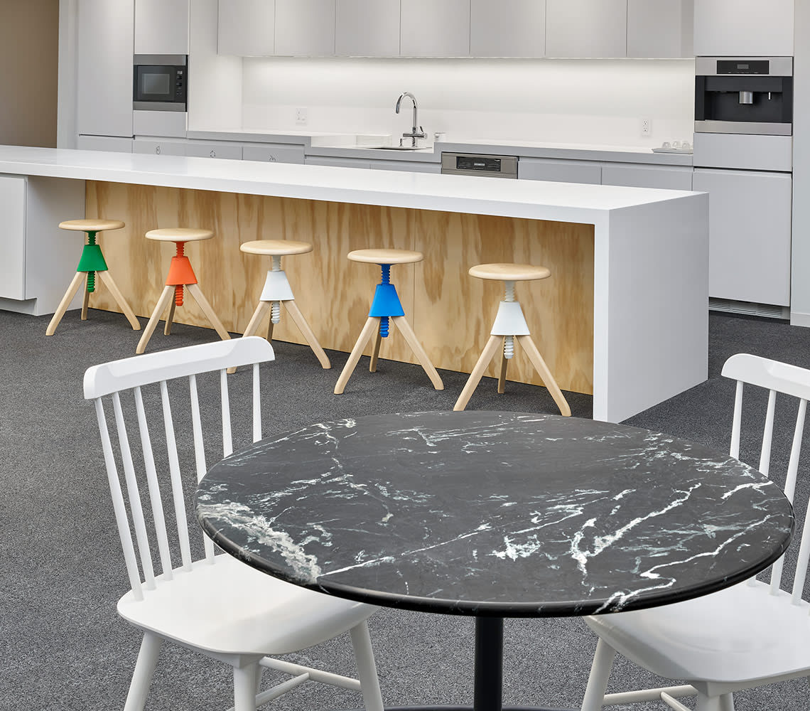 A kitchen featuring a black marble table and white chairs positioned in front of a counter.